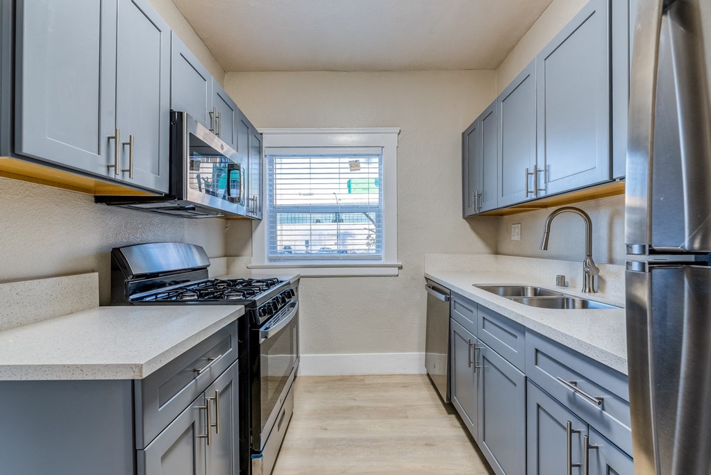 a kitchen with gray cabinets and white countertops