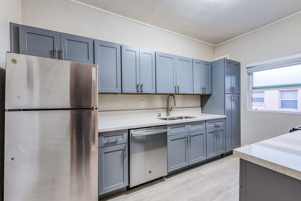 a kitchen with gray cabinets and stainless steel appliances