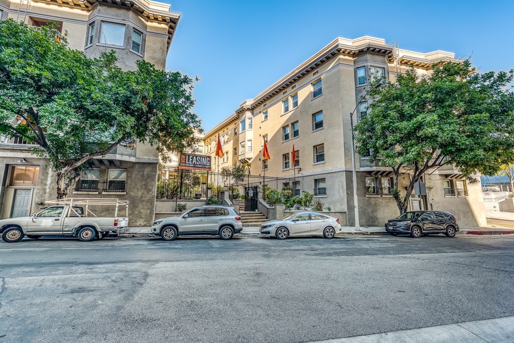 a city street with cars parked on the side of the road and a building in the background