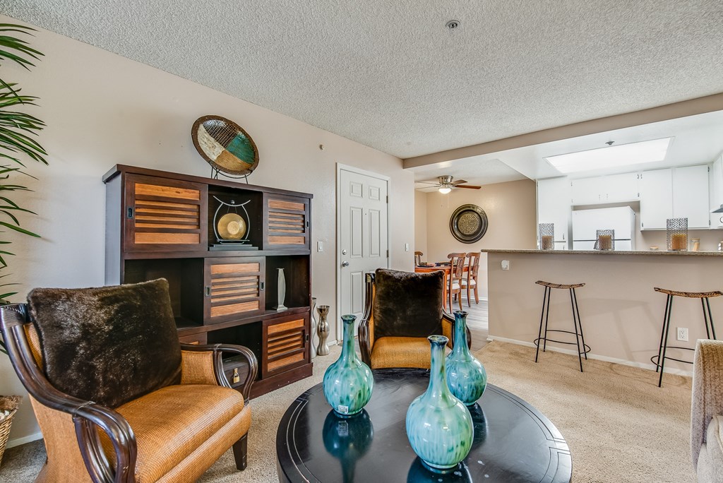 a living room with a table and chairs and a kitchen in the background