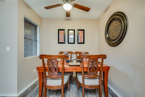 a dining room table with four chairs and a ceiling fan