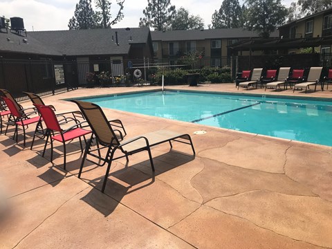a swimming pool with red chairs and a blue pool