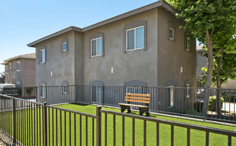 A brown building with a black fence and a bench in front.
