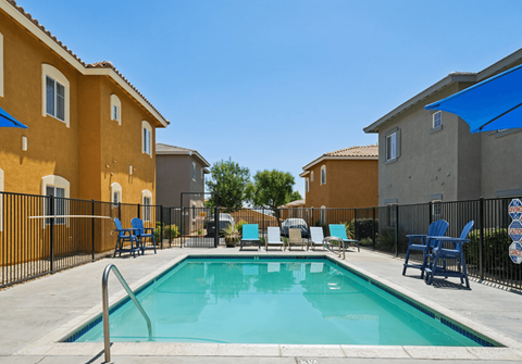 A swimming pool surrounded by chairs and buildings.
