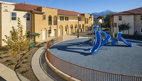 A playground with a blue slide in front of a building.