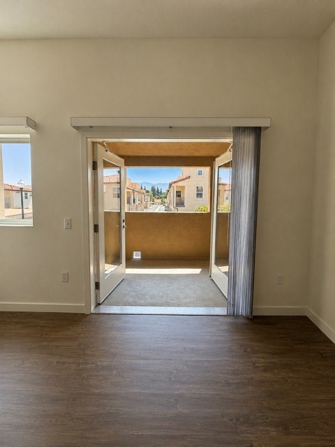 A room with a wooden floor and a view of a street through a sliding glass door.