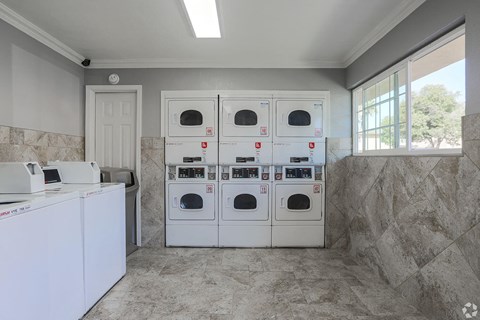 A kitchen with white appliances and a tiled floor.
