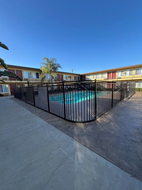 A pool surrounded by a black fence in front of a building.