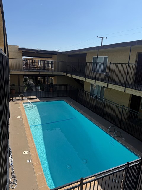 A small pool in a courtyard surrounded by a black fence.