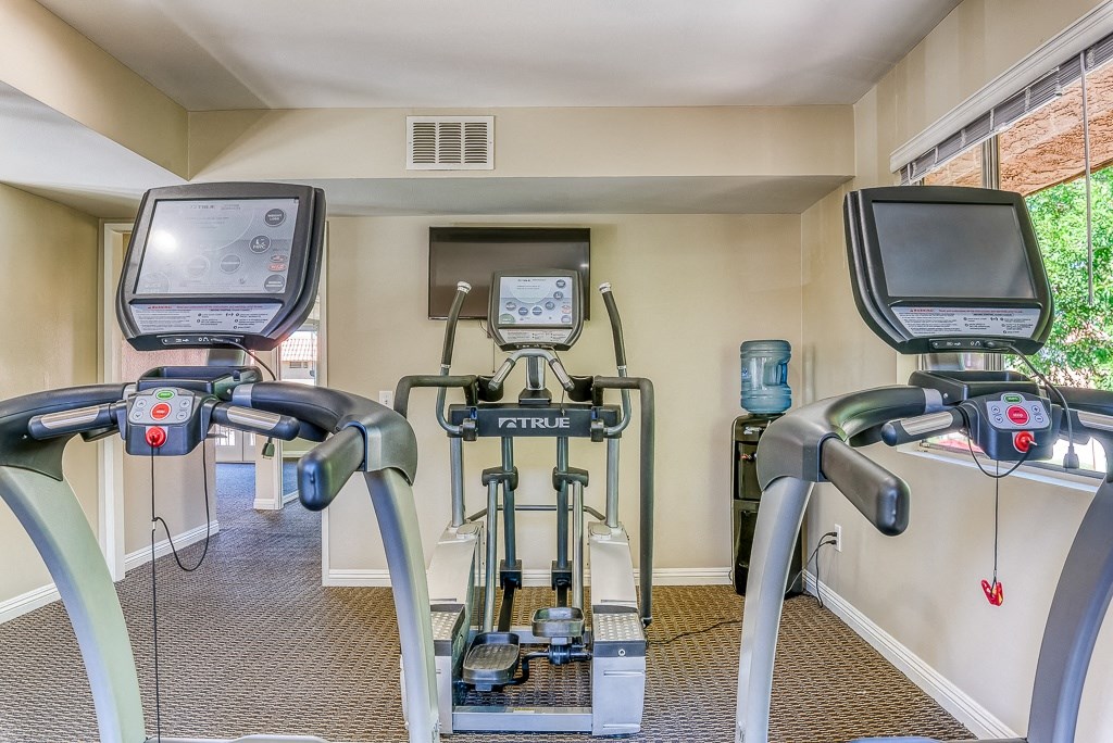 A treadmill and a stationary bike are in a gym.