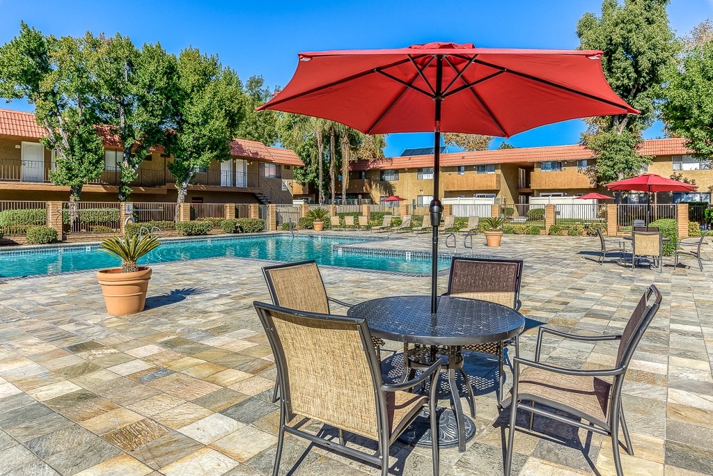A patio with a table and chairs and an umbrella.