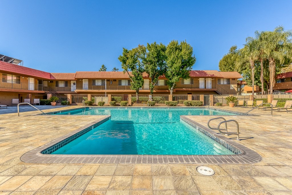 A large swimming pool in front of a building with a red roof.