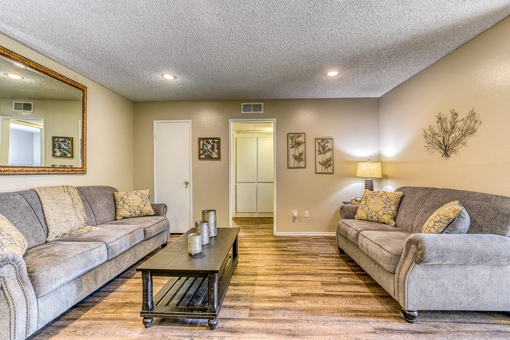 A living room with two couches, a coffee table, and a large mirror.