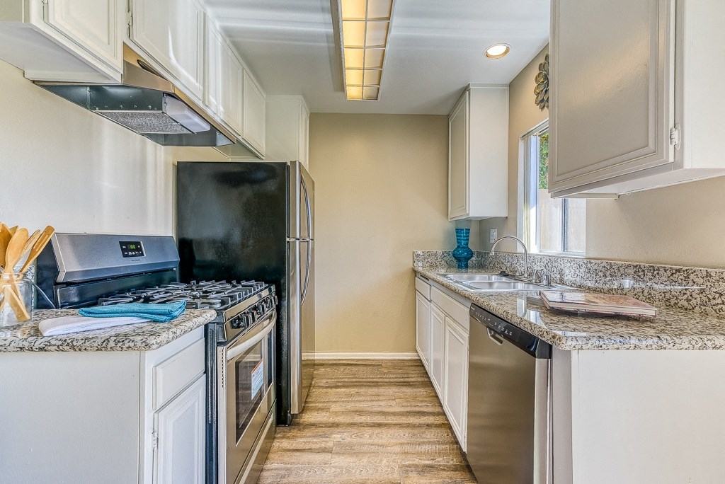 A kitchen with a black fridge, stove, and oven.