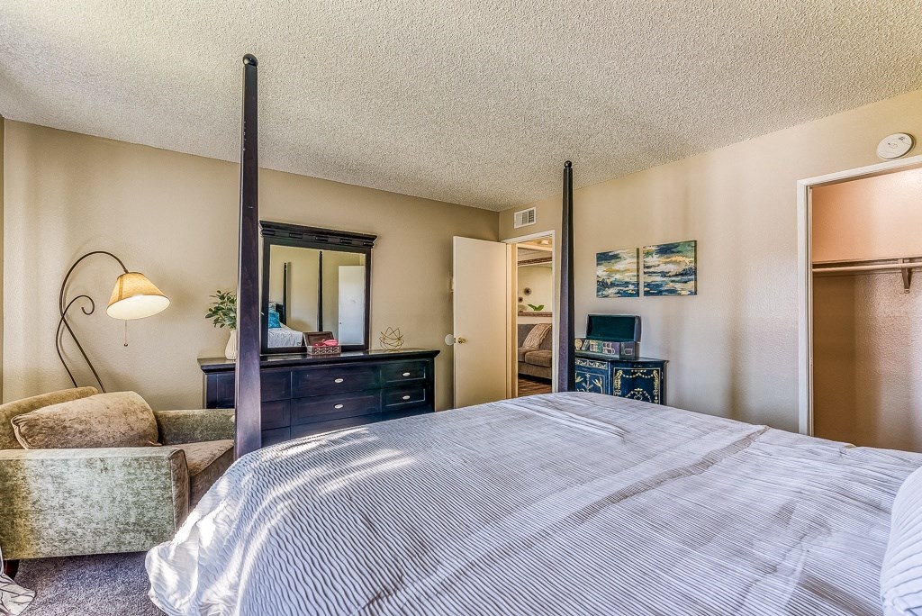 A bedroom with a large bed, a dresser, and a chair.