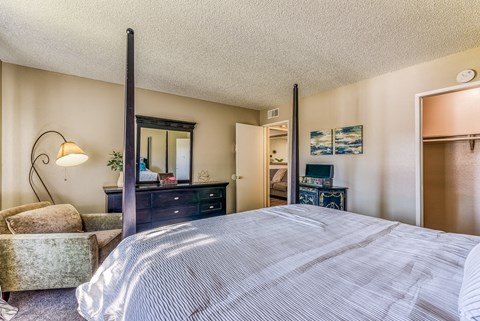 A bedroom with a large bed, a dresser, and a chair.
