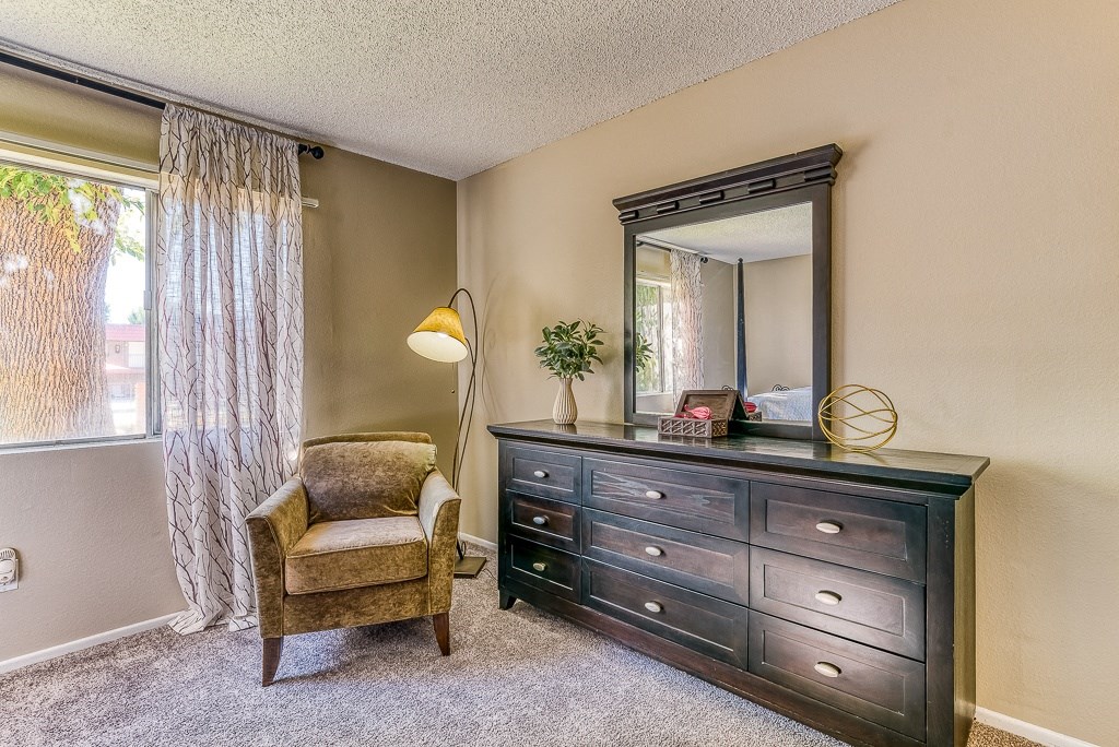 A chair, a dresser, and a mirror are in a room.