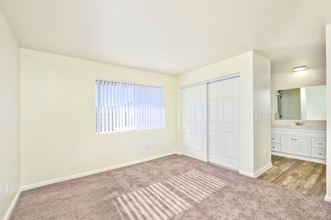 A bedroom with a large window and a dresser with a mirror.