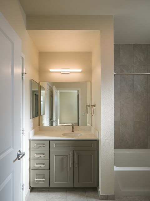 A bathroom with a sink, mirror, and bathtub.