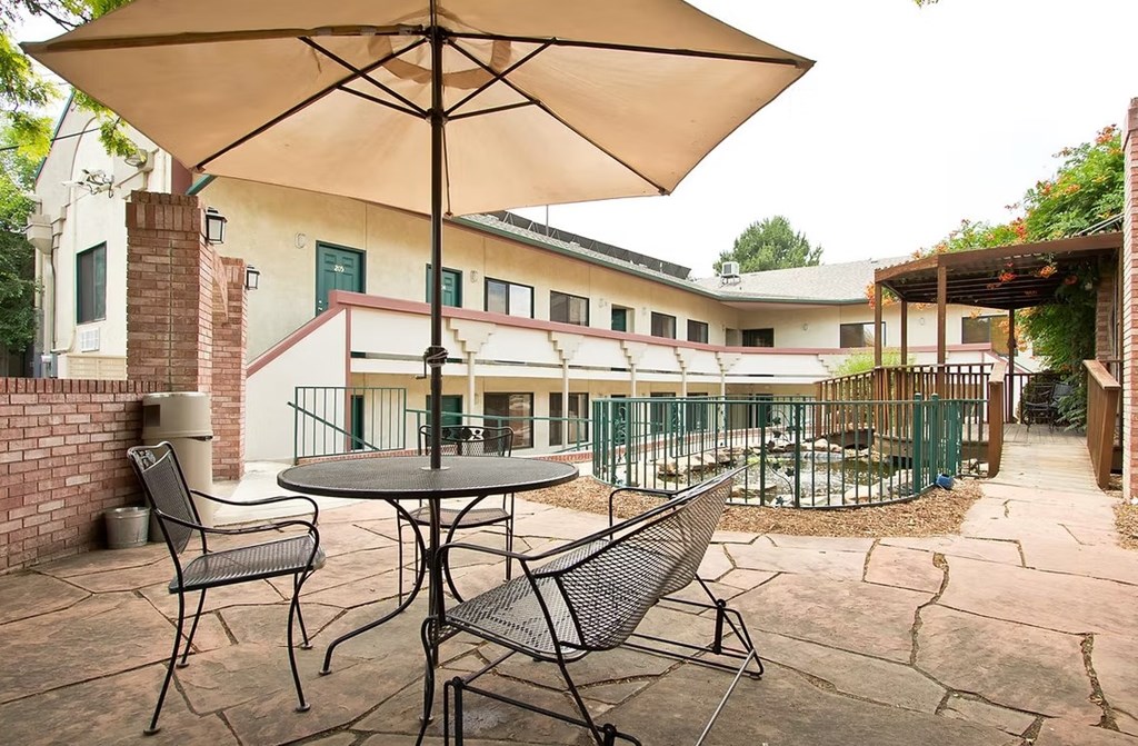 A patio with a table and chairs under an umbrella.