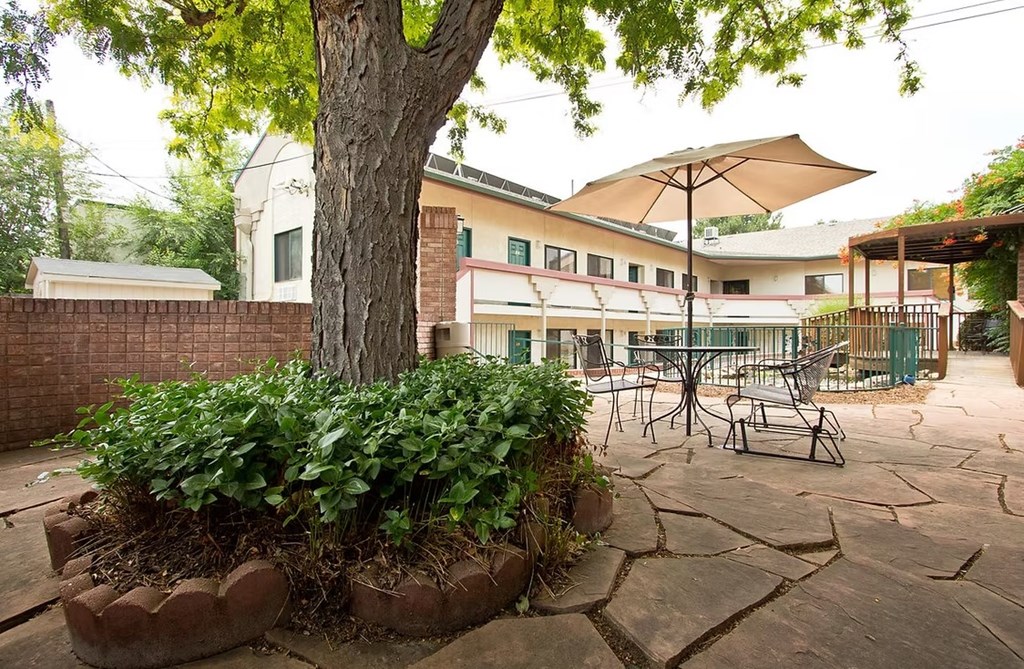 A patio with a table and chairs under an umbrella.