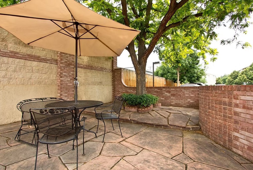 A patio with a table and chairs under an umbrella.