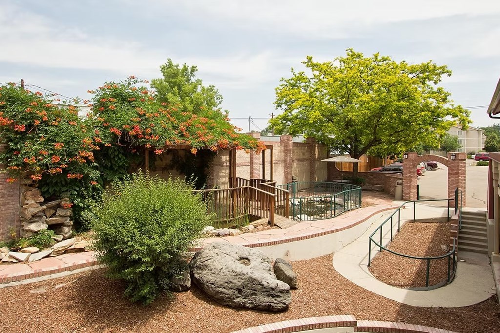 A garden with a large rock in the center and a metal fence surrounding it.