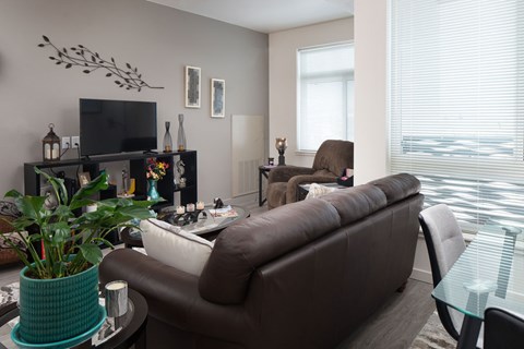 A living room with a brown couch and a glass table.