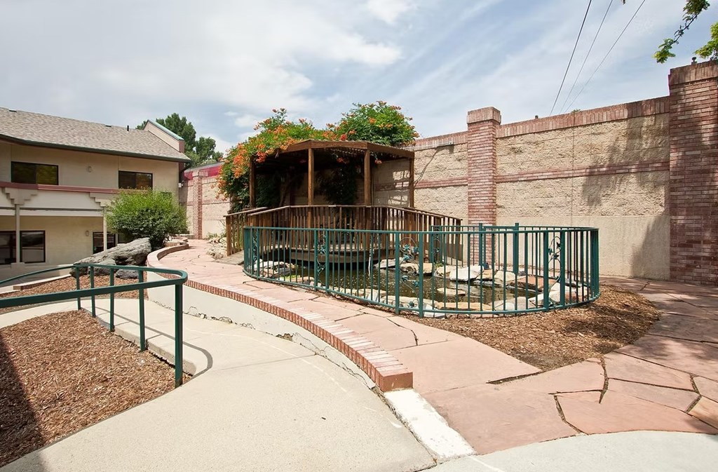 A small garden area with a fence and a small building in the background.