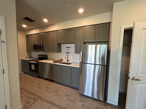 A kitchen with a refrigerator, microwave, and oven.