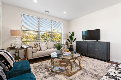 A living room with a glass coffee table and a large couch.