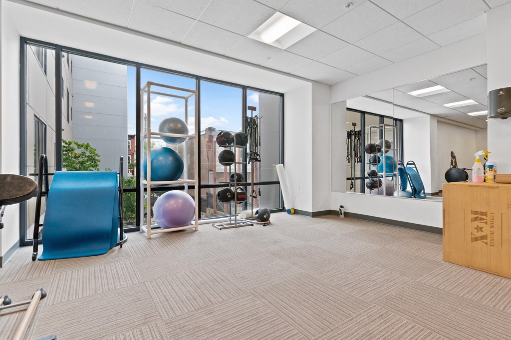 Carpeted yoga room with mats, exercise balls, and sanitation equipment at UCity Flats student apartments