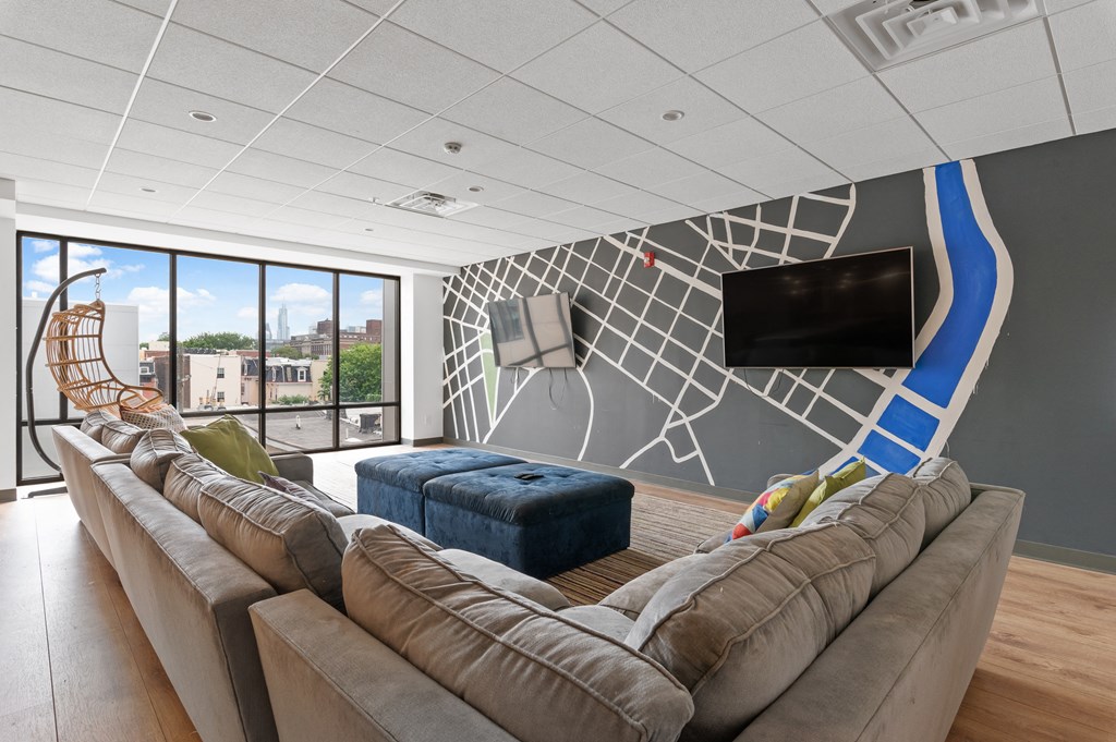 Cozy brown couch and blue ottomans in front of flat screen tv and large windows