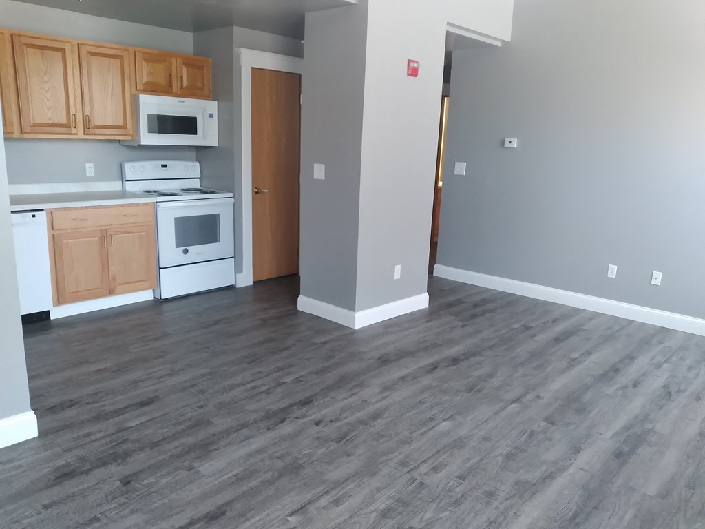 an empty kitchen with wood flooring and white appliances
