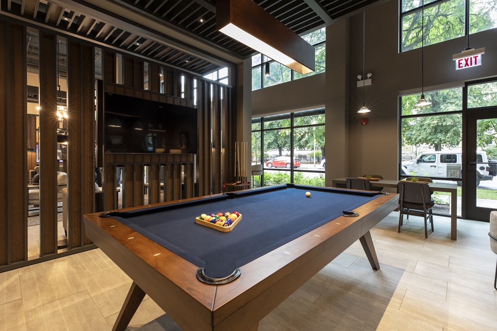 a pool table in a clubhouse with a bar and a television