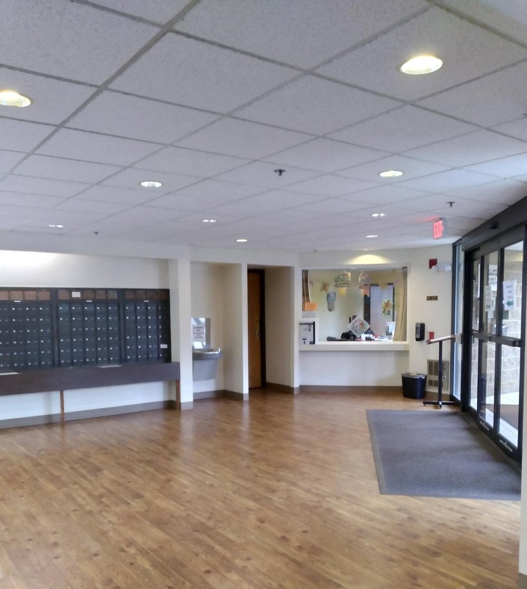 a large room with hardwood floors and a large bulletin board on the wall