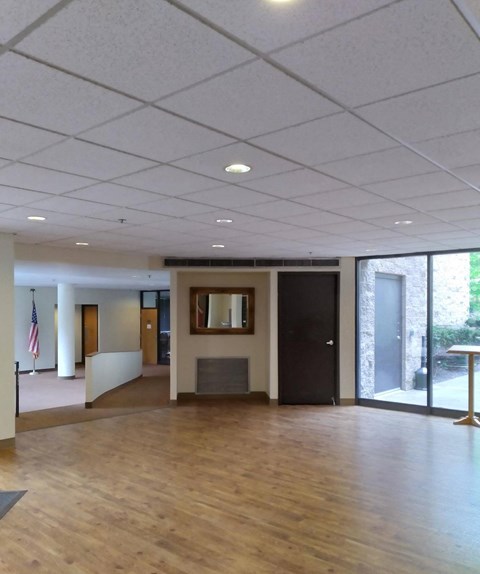 A spacious room with wooden floors and a black door.