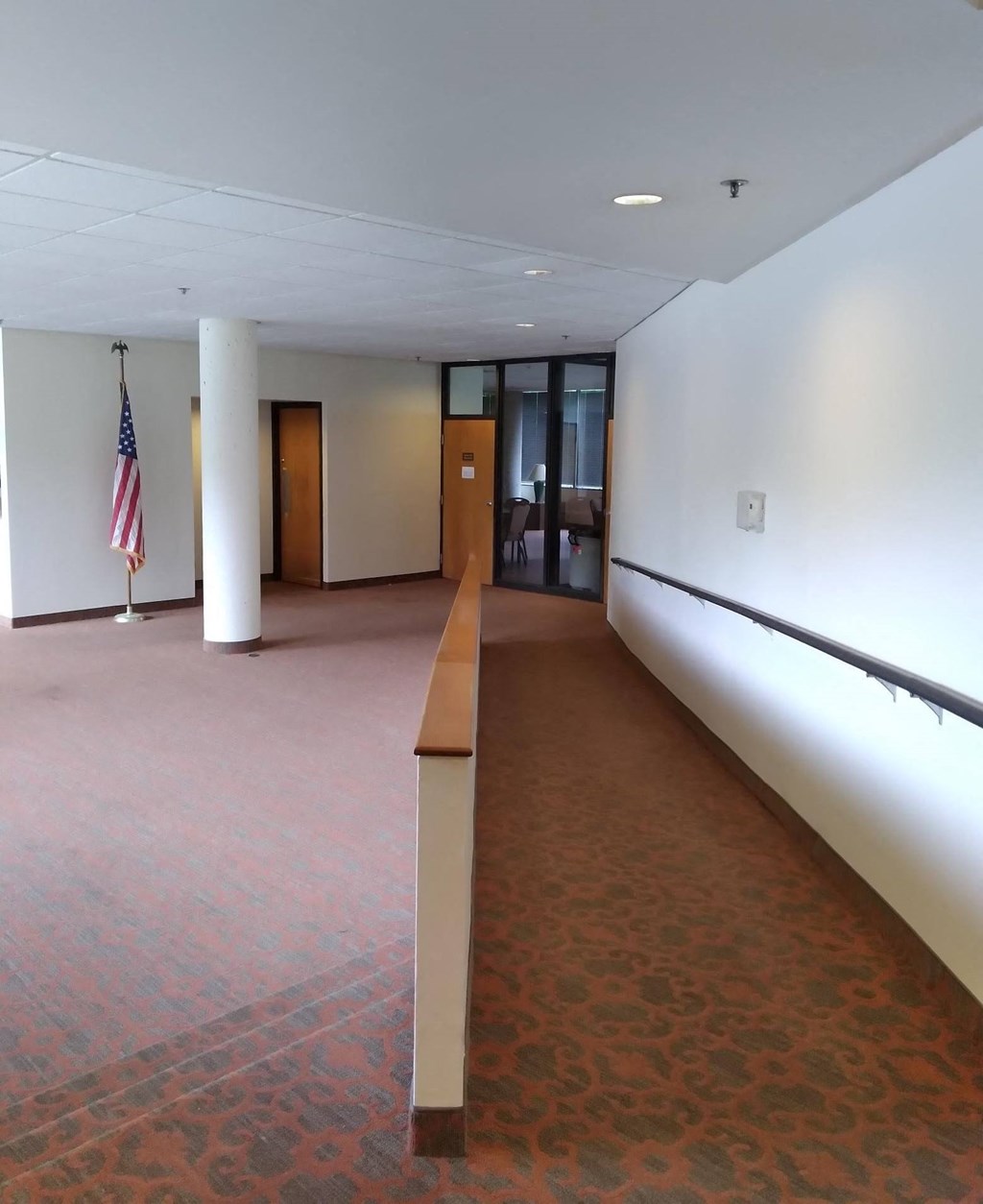 an empty room with a flag on the left and a large window on the right