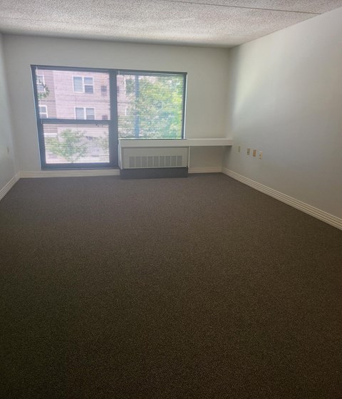 an empty room with a large window and a radiator