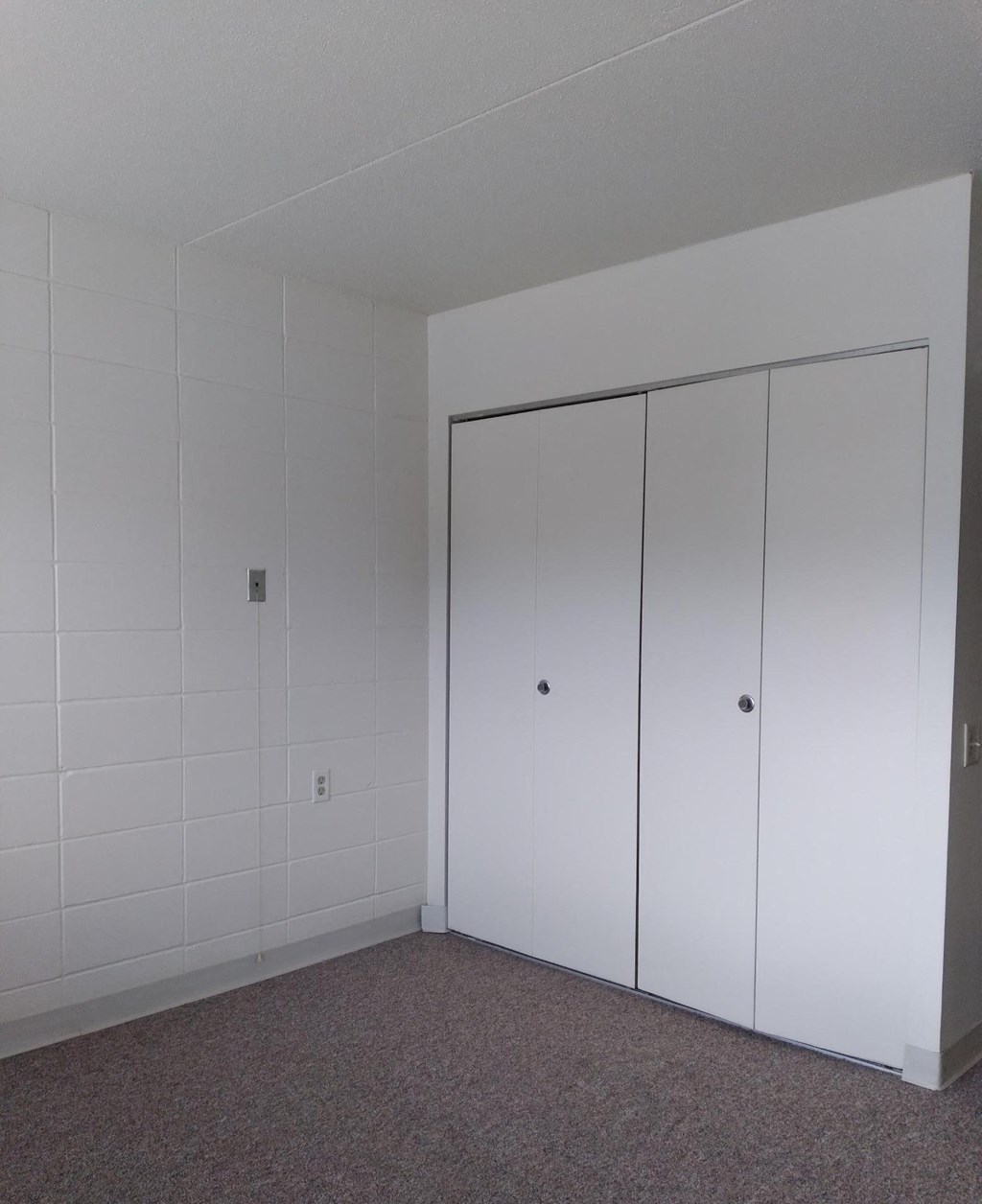 a bedroom with white walls and a white wardrobe with two doors