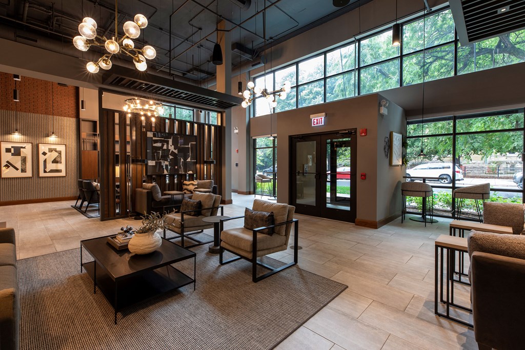 the lobby of a hotel with chairs and tables and large windows