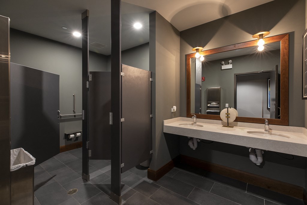 a bathroom with two stalls and a sink and a mirror