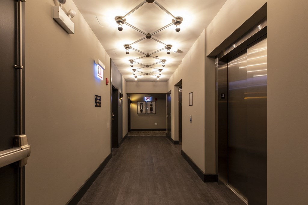 a hallway with elevators and lights on the ceiling in a building