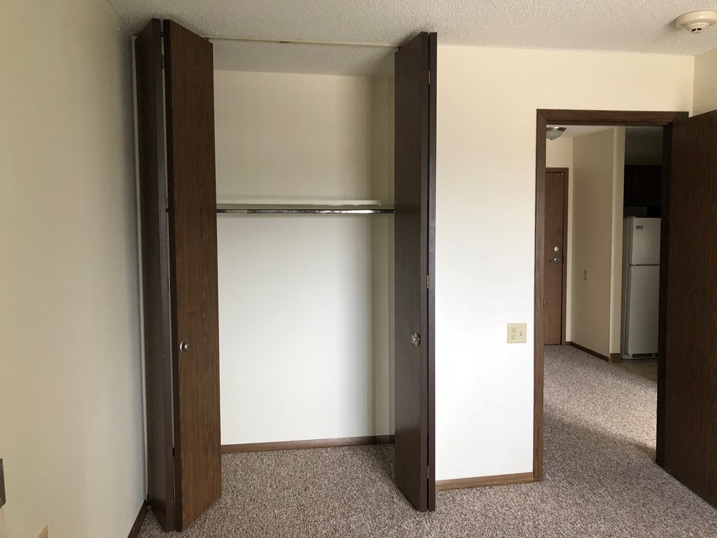 A room with a white wall and a brown closet.
