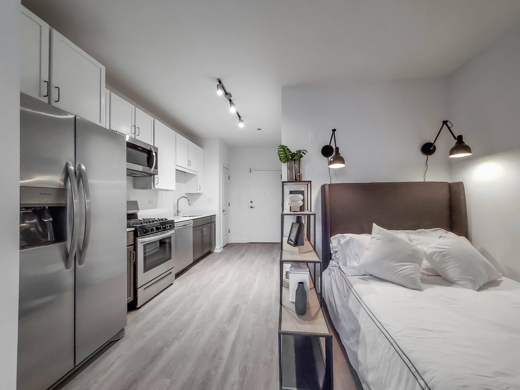 a bedroom with a bed and a kitchen with stainless steel appliances