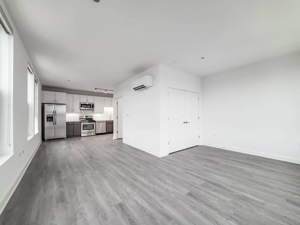 an empty living room with white walls and a kitchen
