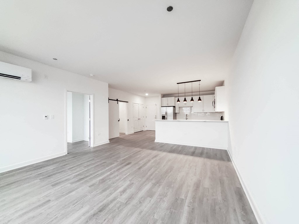 an open kitchen and living room with white walls and wood flooring