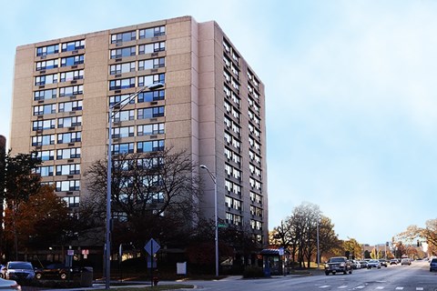 A tall building with many windows is in the background of a street scene.