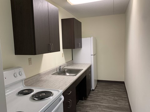 A kitchen with a white stove and dark brown cabinets.