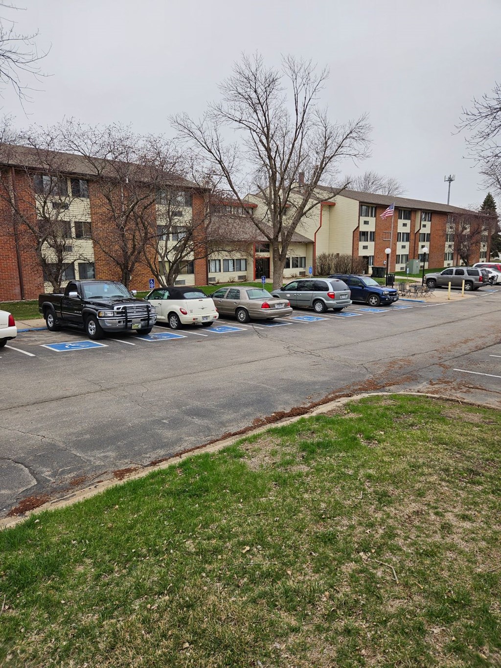 A parking lot with cars and a truck in front of a building.